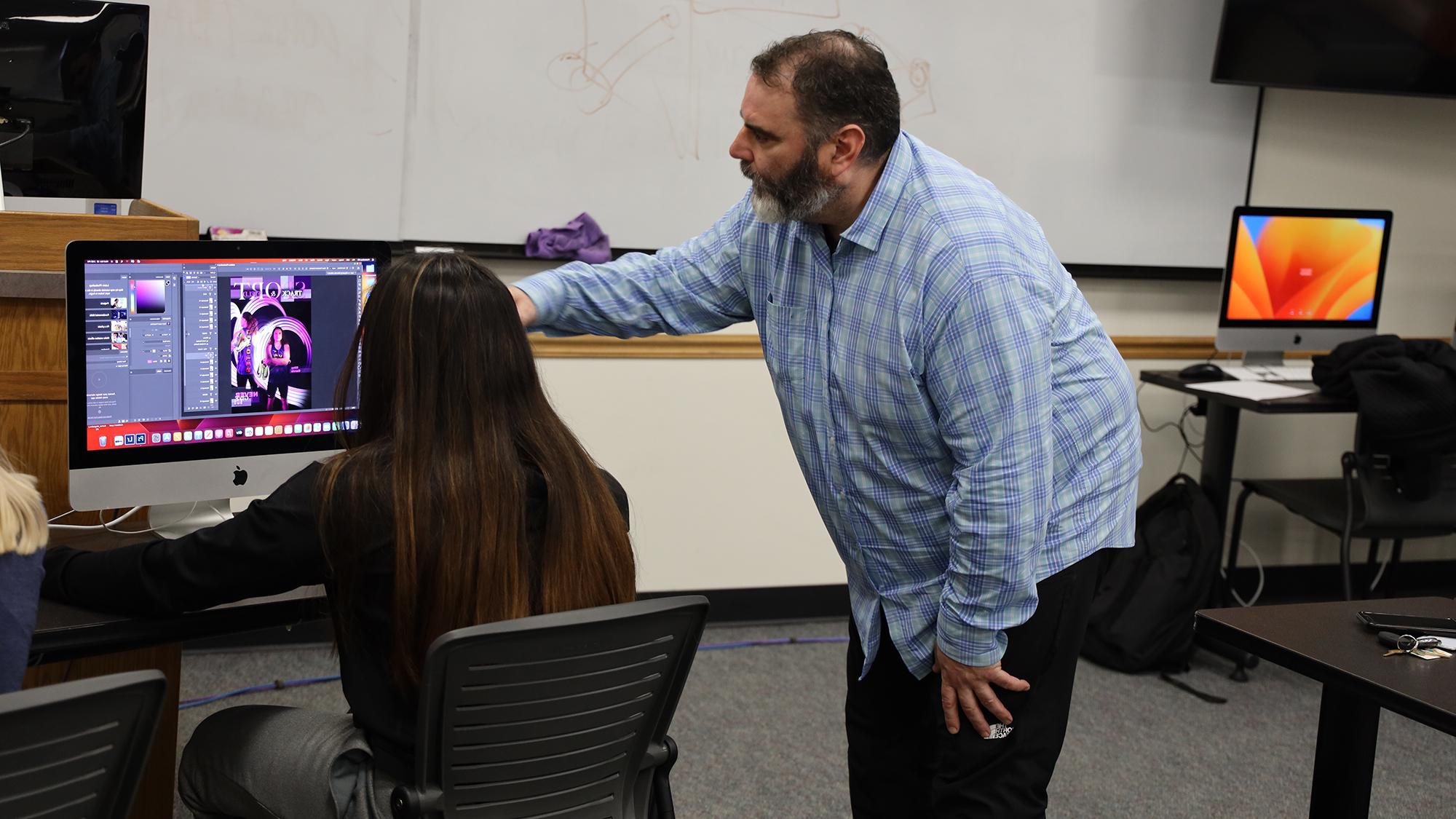 Teacher instructing student on computer