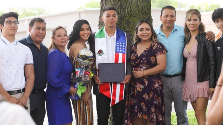Graduate with family by tree